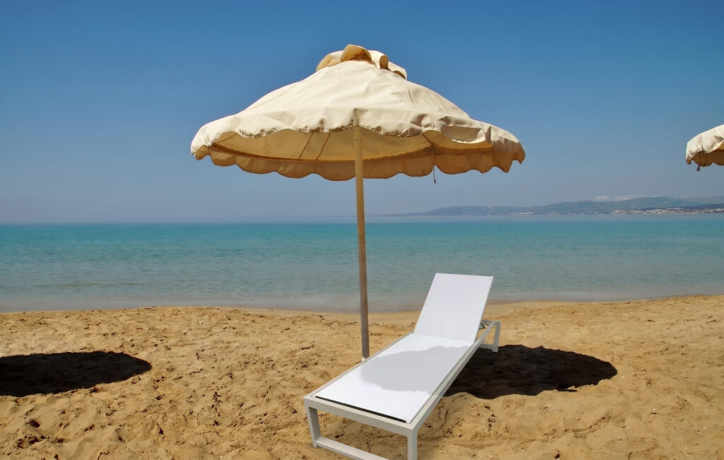 Marbella Essence white sun lounger on a sandy beach with cream parasol and turquoise sea